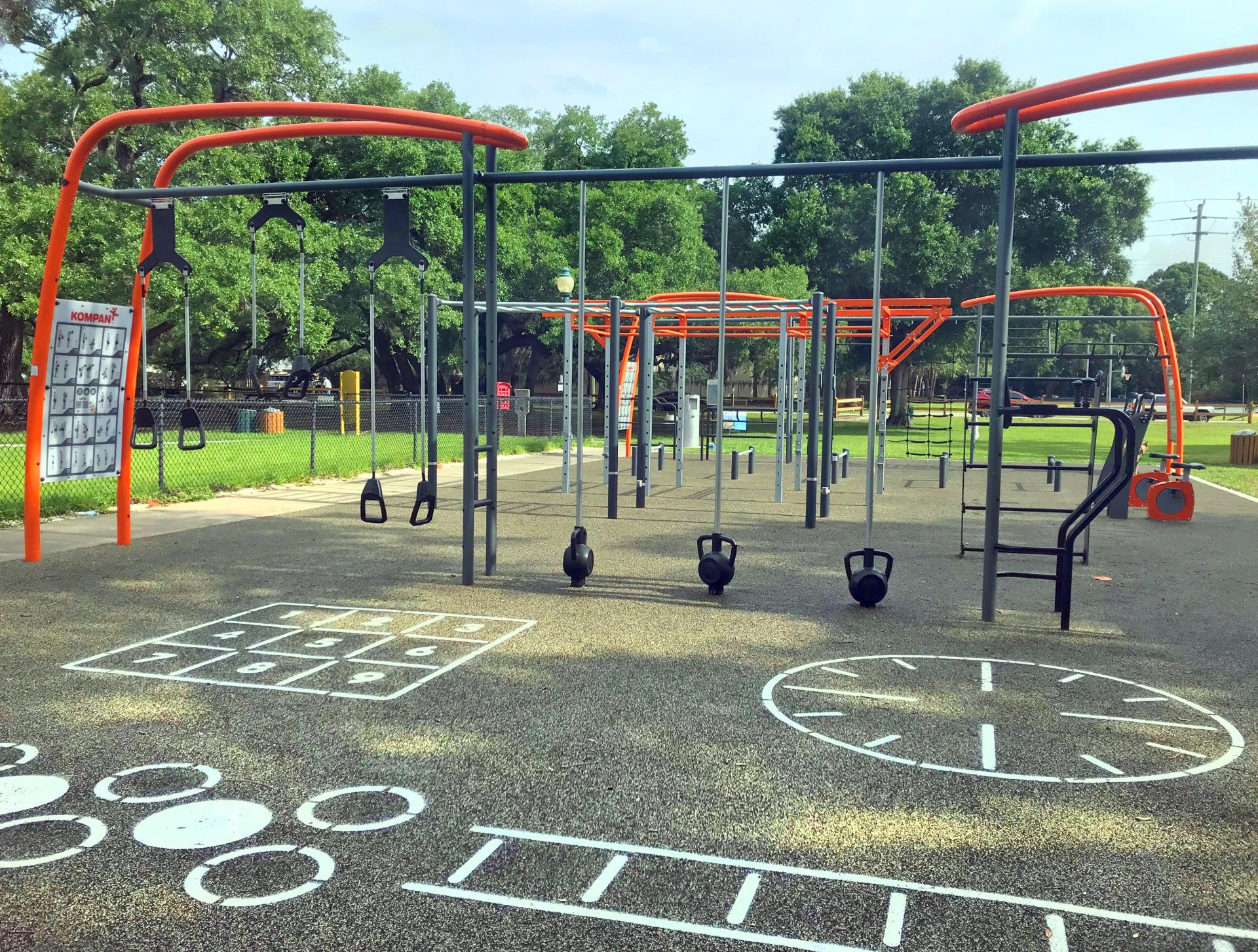 Outdoor Fitness Area inside arlington park colors of orange and black create a jungle gym of fitness stations on a beautiful day in the park.