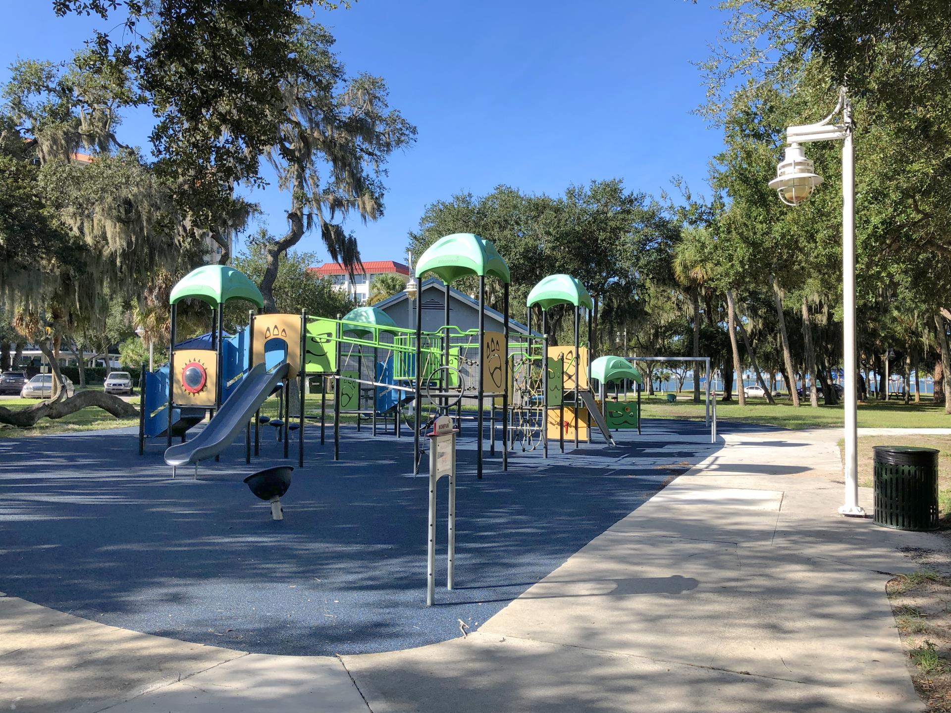 Playground with surface new color blue. Playground is yellow blue green and black with a slide and swings on a sunny day.